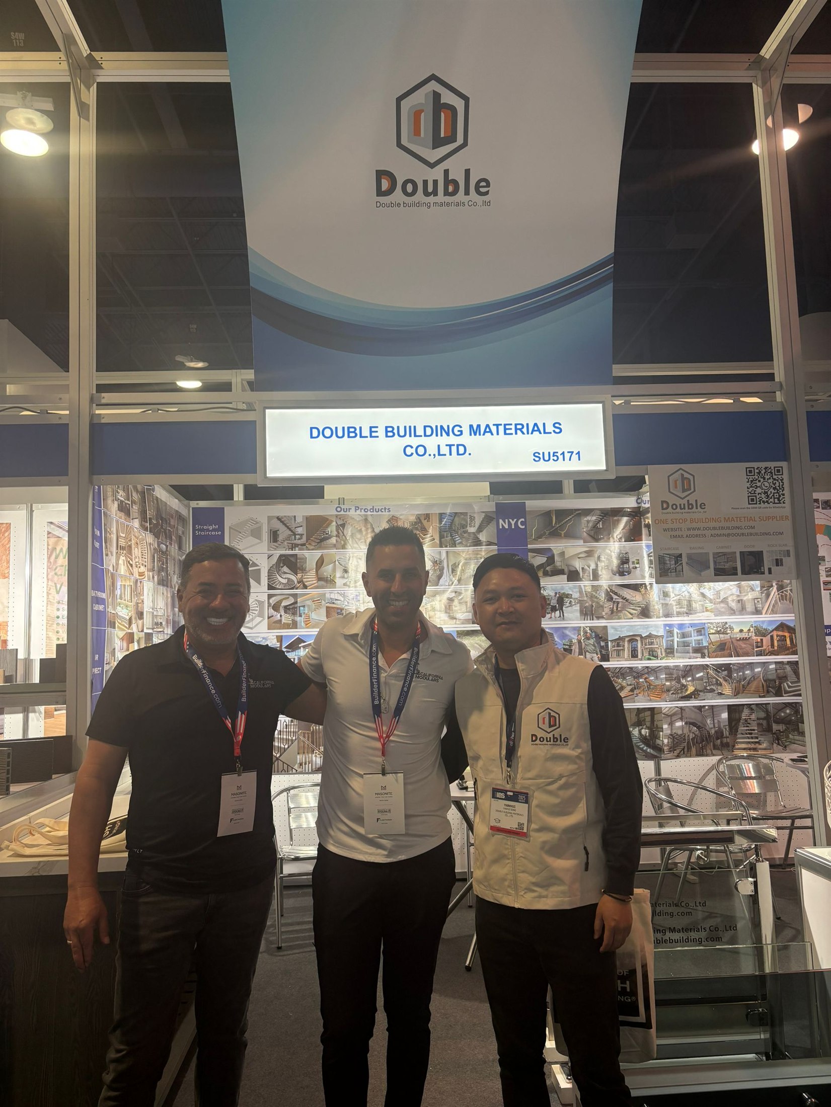 Staff and a visitor standing together at booth SU5171 in front of the product wall