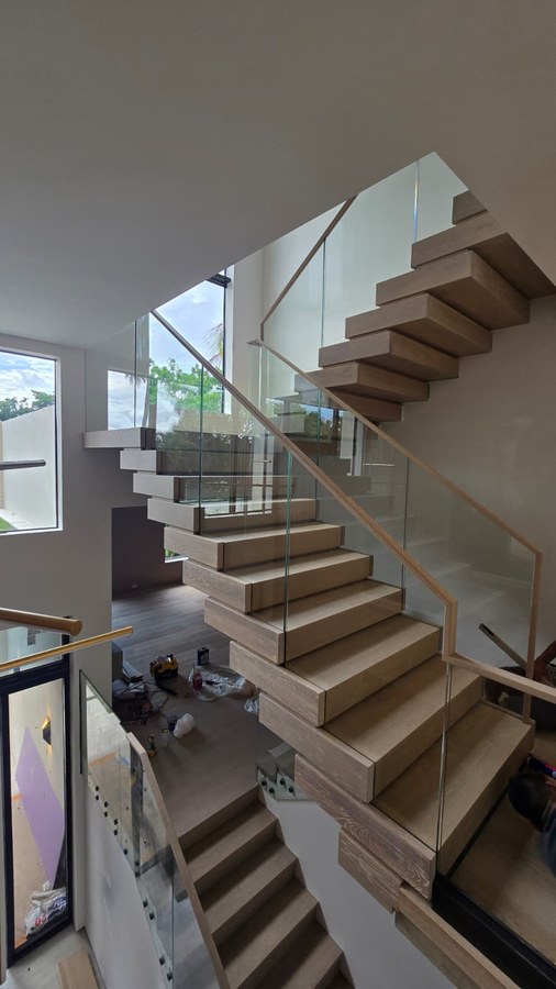 Multi-flight stacked oak staircase landing with glass and wood rail during late install
