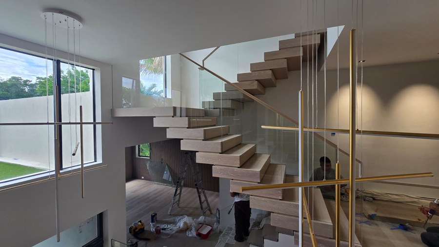 Stacked white oak switchback staircase with frameless glass and wood handrail in a Florida home