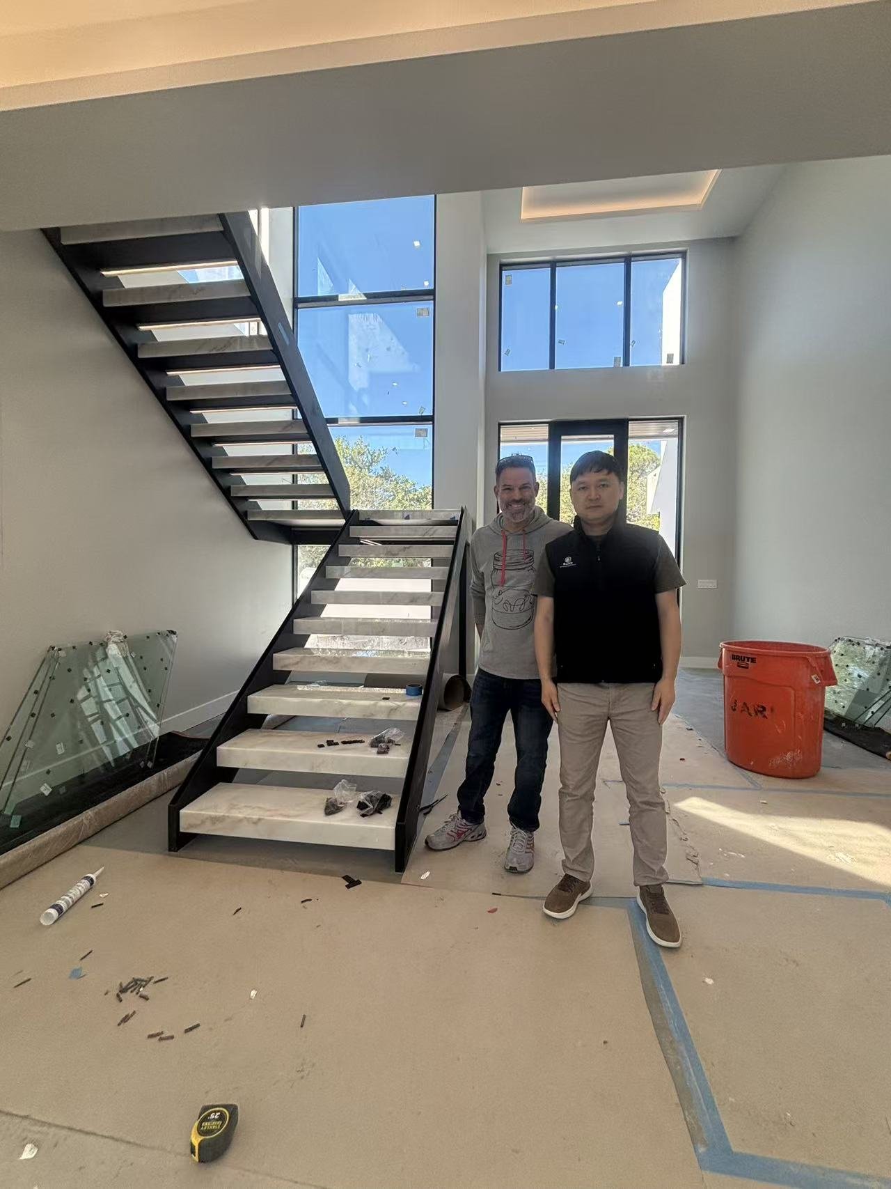 Factory staff with a project contact beside a stone staircase mid-install