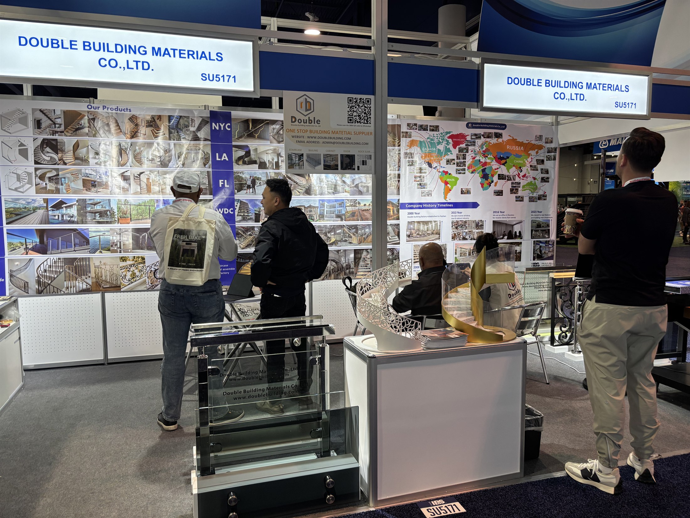Double Building booth SU5171 with a world-map wall, catalogues and visitors
