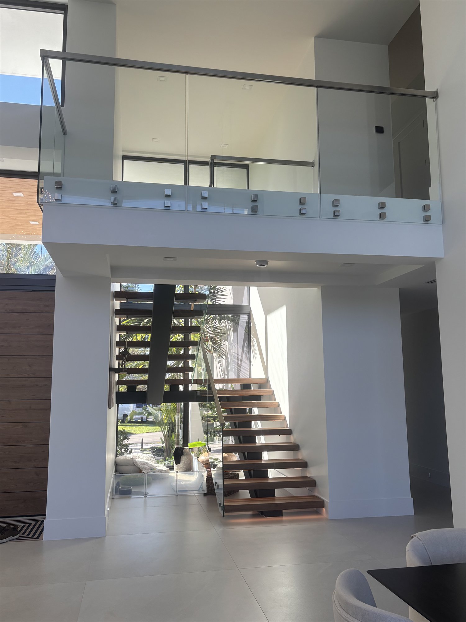 Glass railing on an upper landing above a floating wood staircase