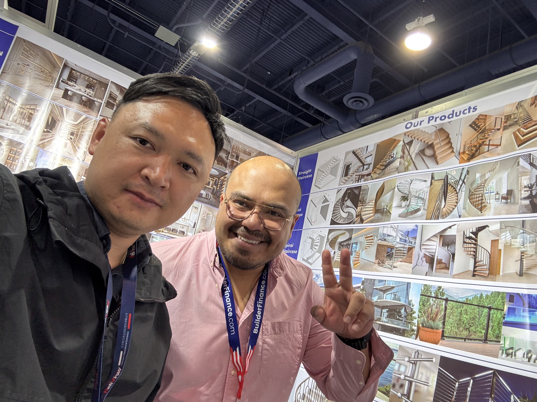 Staff selfie with a visitor at the product wall