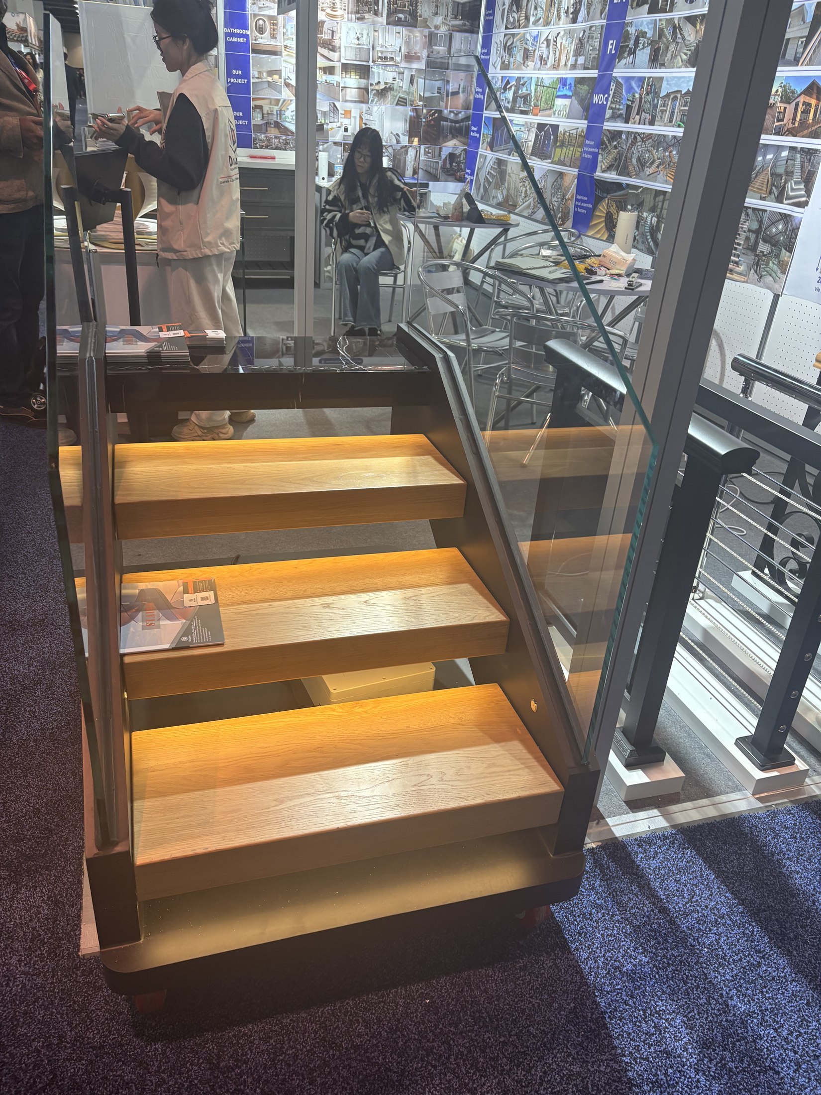 Floating staircase sample with wood treads, glass railing and under-tread light at the IBS 2025 booth