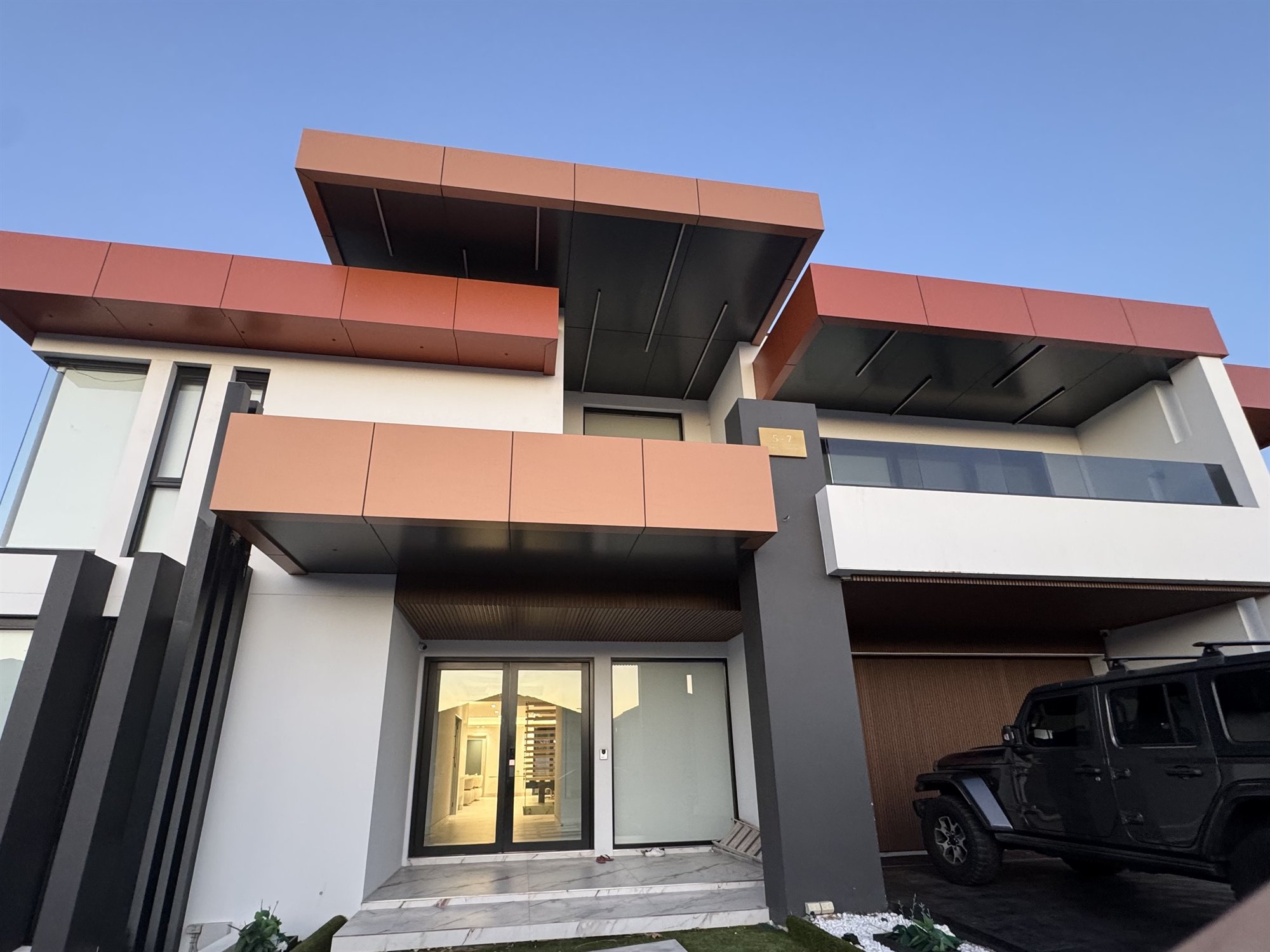 Finished Sydney house front with a glass balcony and a staircase visible through the entry glass