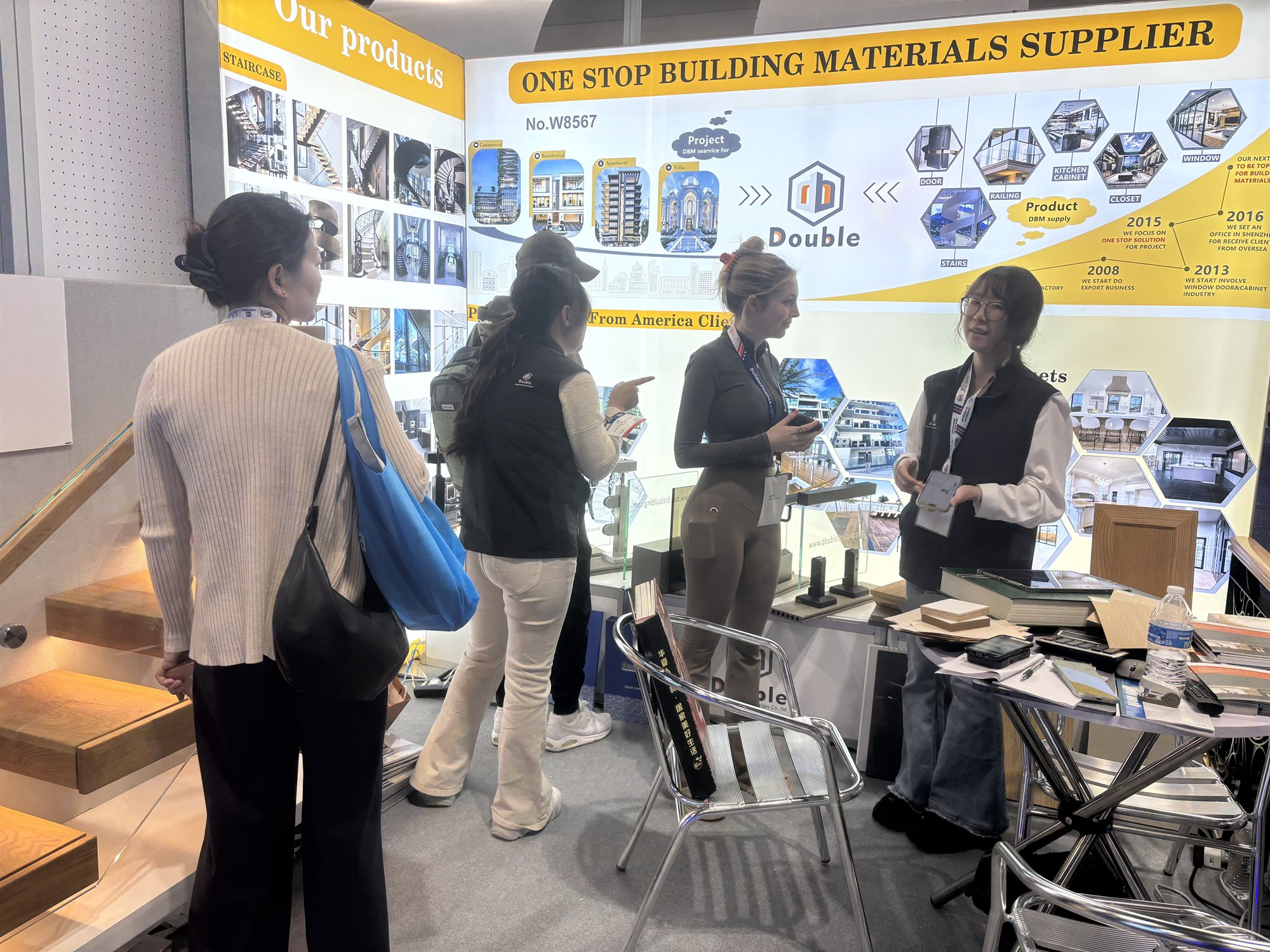 Staff explaining the project wall to visitors at the booth