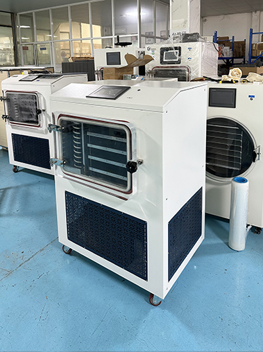 Right perspective view of a white lyophilizer machine with an integrated square drying chamber parked on a blue industrial workshop floor.