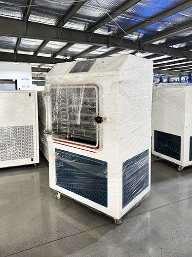 Right perspective view of a laboratory freeze dryer wrapped in protective film inside a manufacturing facility.