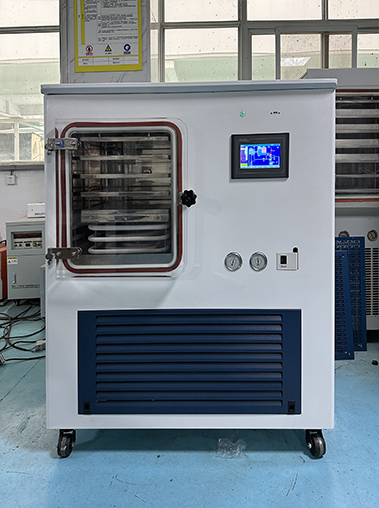 Front view of a vacuum freeze dryer operating inside a manufacturing facility, featuring an active digital touch control screen.