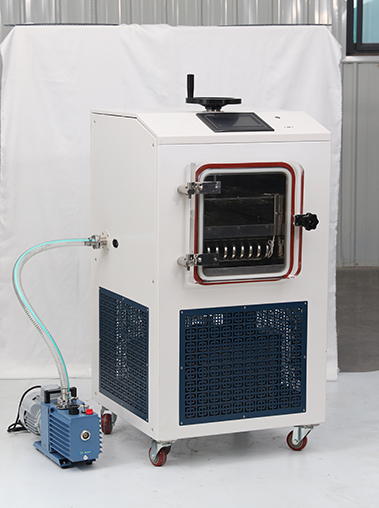 Perspective real shot of a white cabinet laboratory freeze dryer with a top stoppering handle and connected blue vacuum pump against a white studio backdrop.