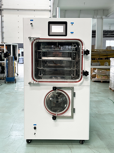 Straight front view real shot of a pilot freeze dryer lyophilizer machine, showcasing its upper square drying chamber, integrated touch screen, and round lower cold trap.
