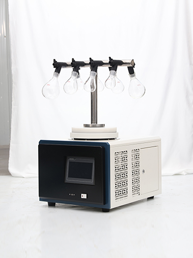 Angled side view of Geliss vacuum freeze dryer with T-shaped manifold showing side mesh ventilation, cream metal casing, black front panel, and top glass flasks.