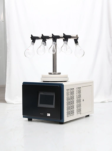 Angled side view of Geliss vacuum freeze dryer with T-shaped manifold showing side mesh ventilation, cream metal casing, black front panel, and top glass flasks.