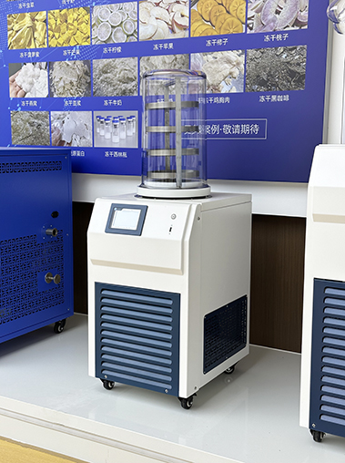 Left-side angled showroom shot of a standard laboratory freeze dryer lyophilizer, showcasing its white cabinet design and blue ventilation grilles on a display platform.