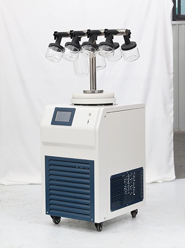 Right angled real shot of a T-frame laboratory freeze dryer showing hanging wide-mouth glass flasks and a blue front ventilation grid against a white backdrop.