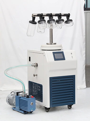 Front view real shot of a T-frame laboratory freeze dryer equipped with clear wide-mouth glass bottles and connected to a blue vacuum pump.