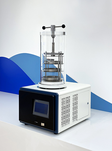 Angled side view of Geliss benchtop vacuum freeze dryer showing its cream-colored metal body, side air vents, and clear chamber with a stoppering mechanism.
