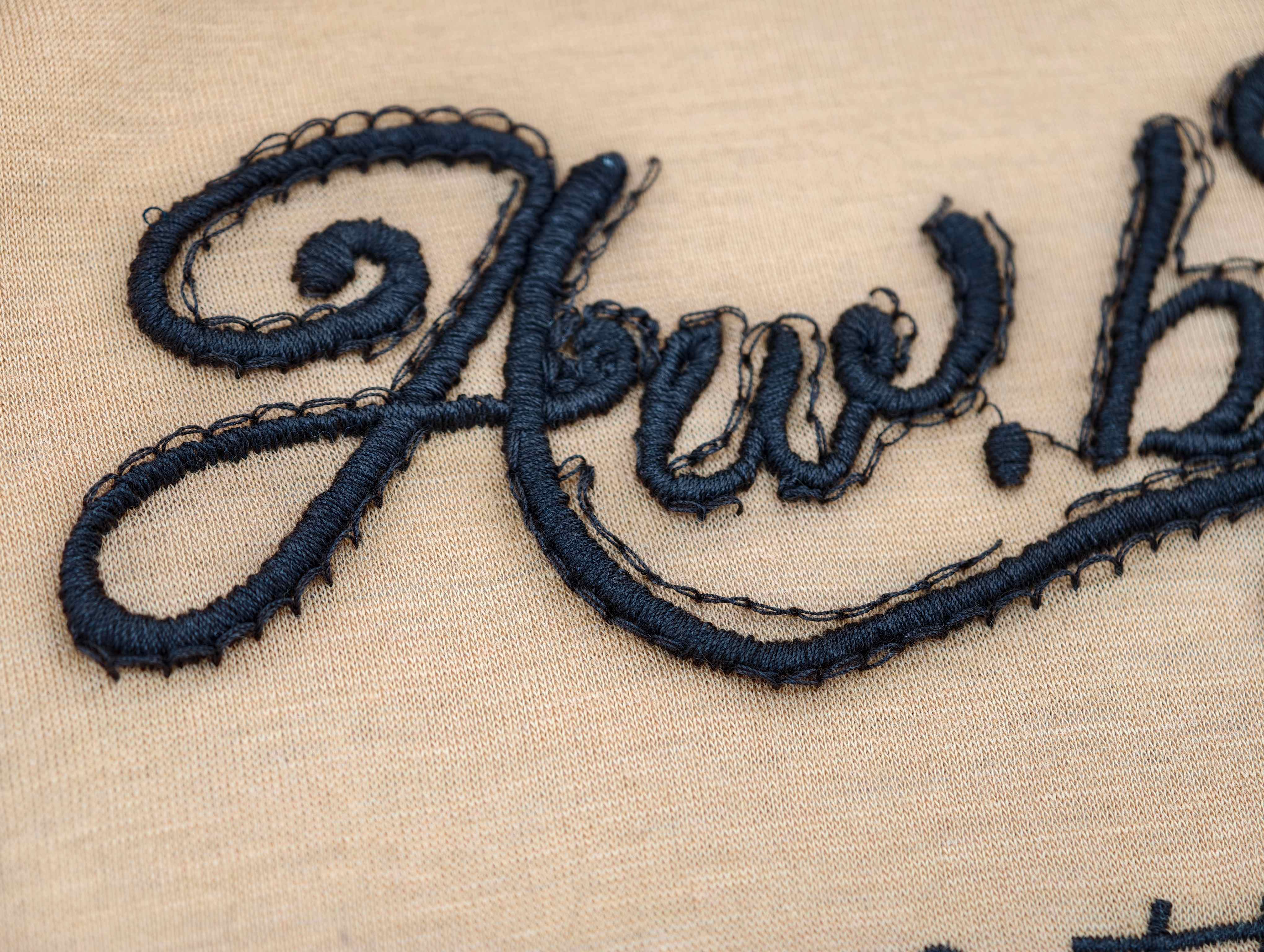 Script embroidery detail with visible backing stitches