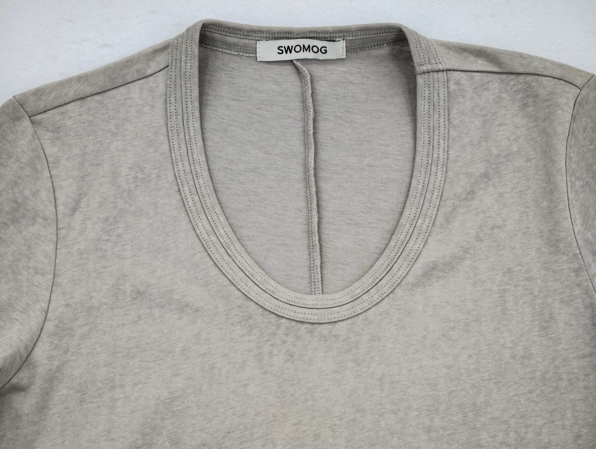Reinforced neckline binding with centered woven label