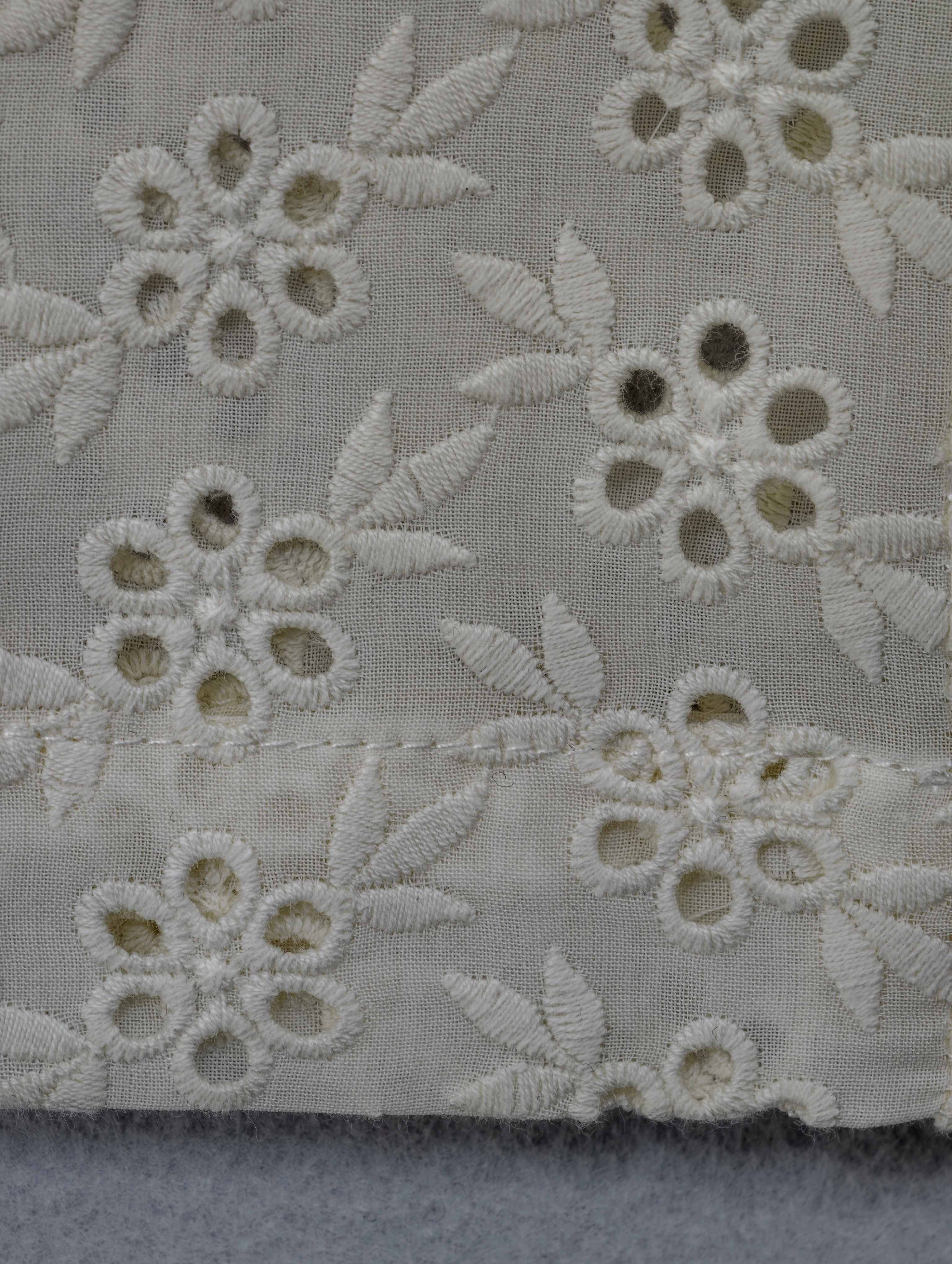 Floral cutwork embroidery and stitched hem close-up