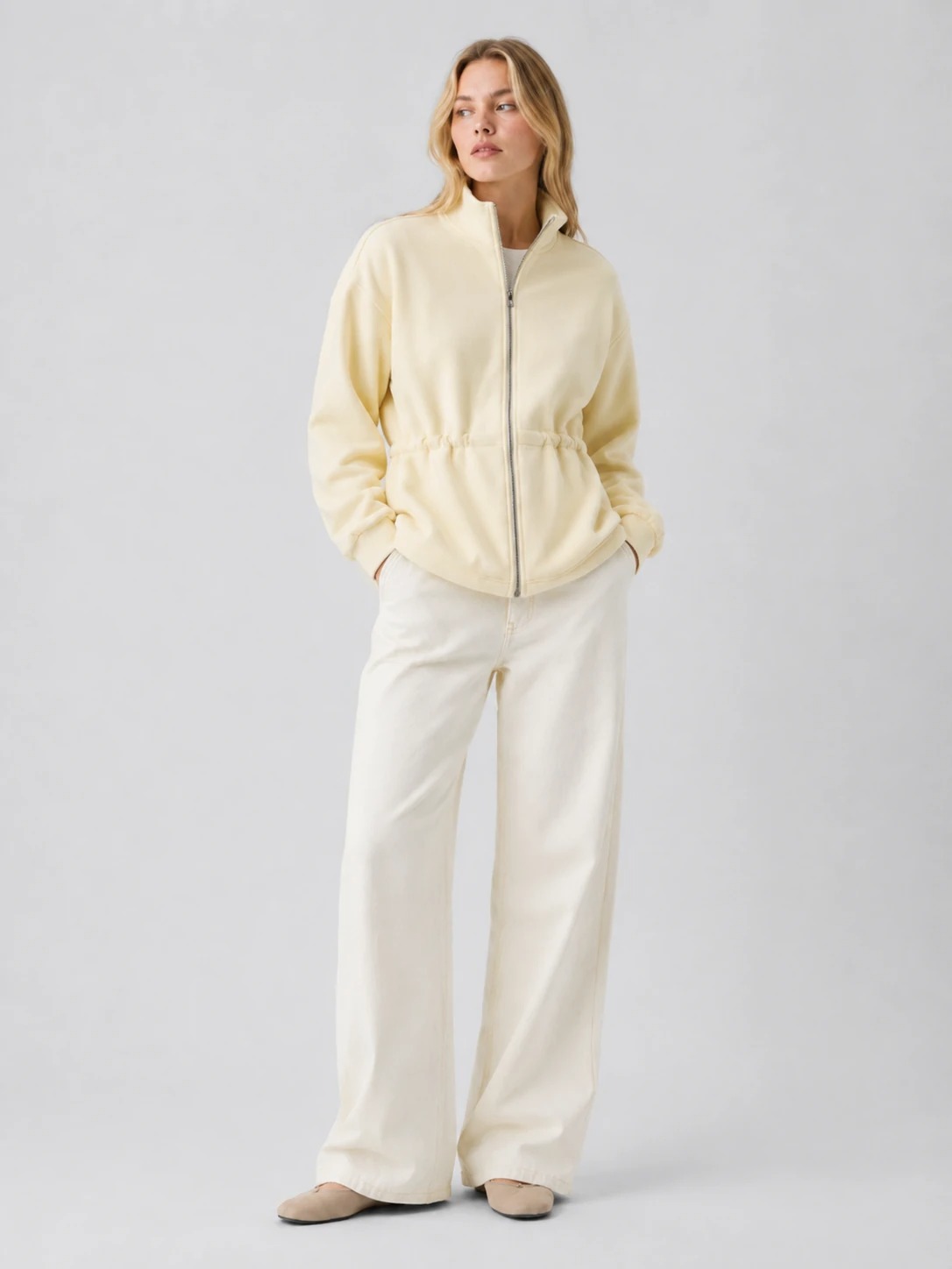 Model wearing cream cinched-waist full-zip sweatshirt jacket