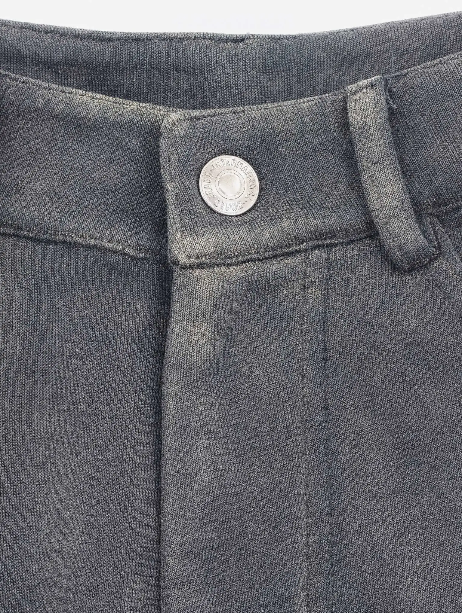 Metal button and waistband detail on charcoal pants