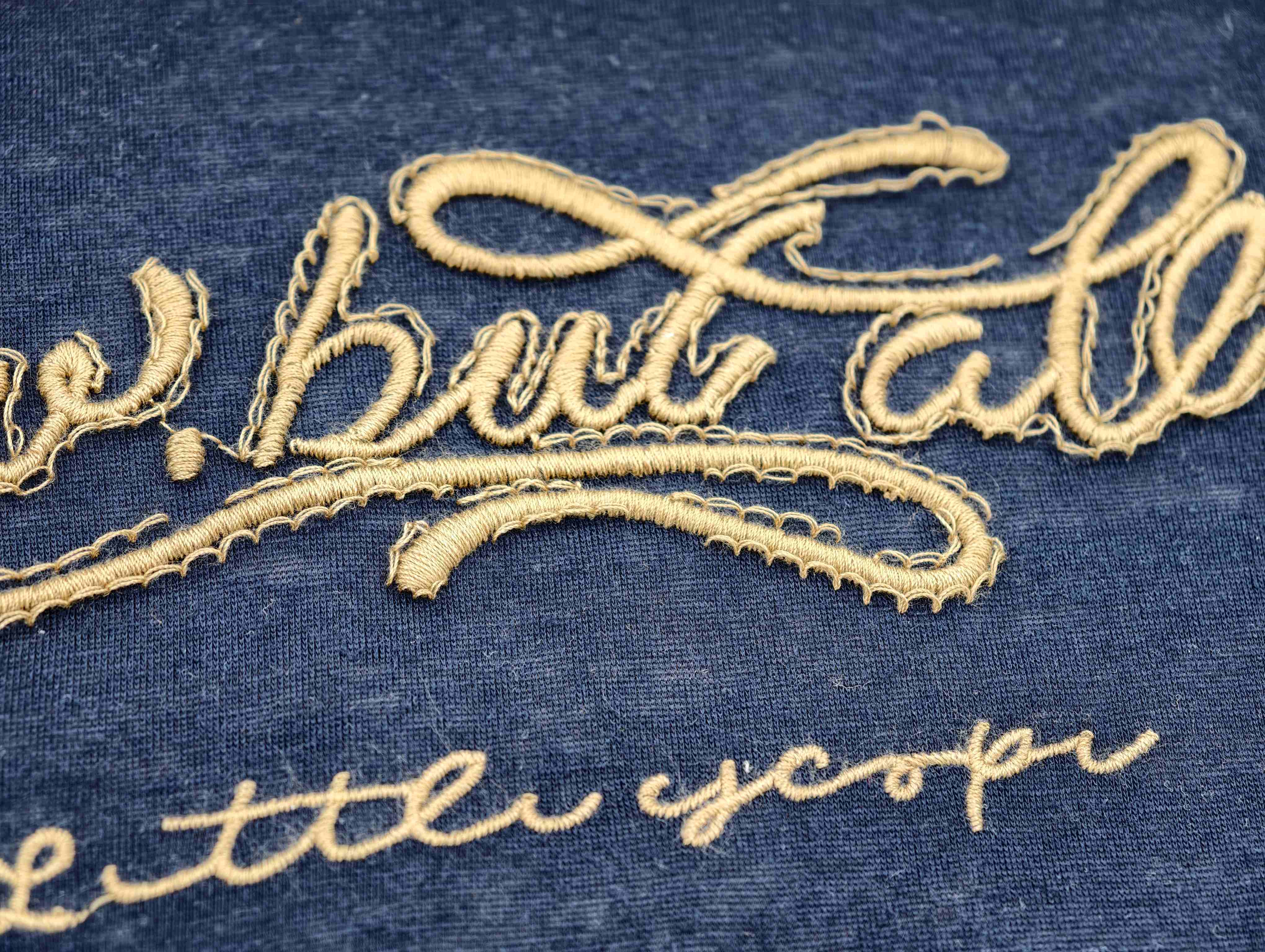 Raised beige script embroidery on soft navy jersey