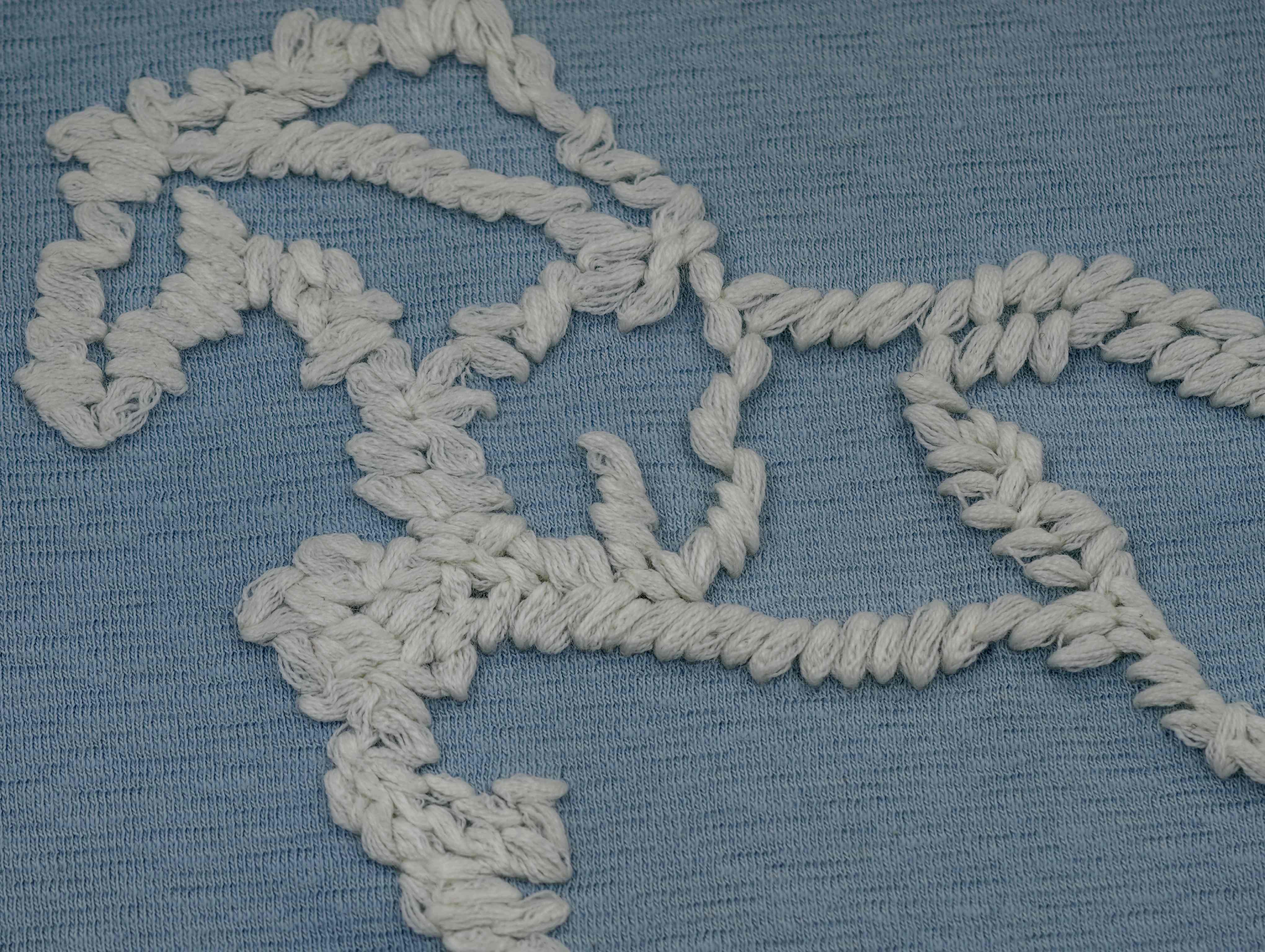 Raised white horse embroidery detail on blue jersey fabric