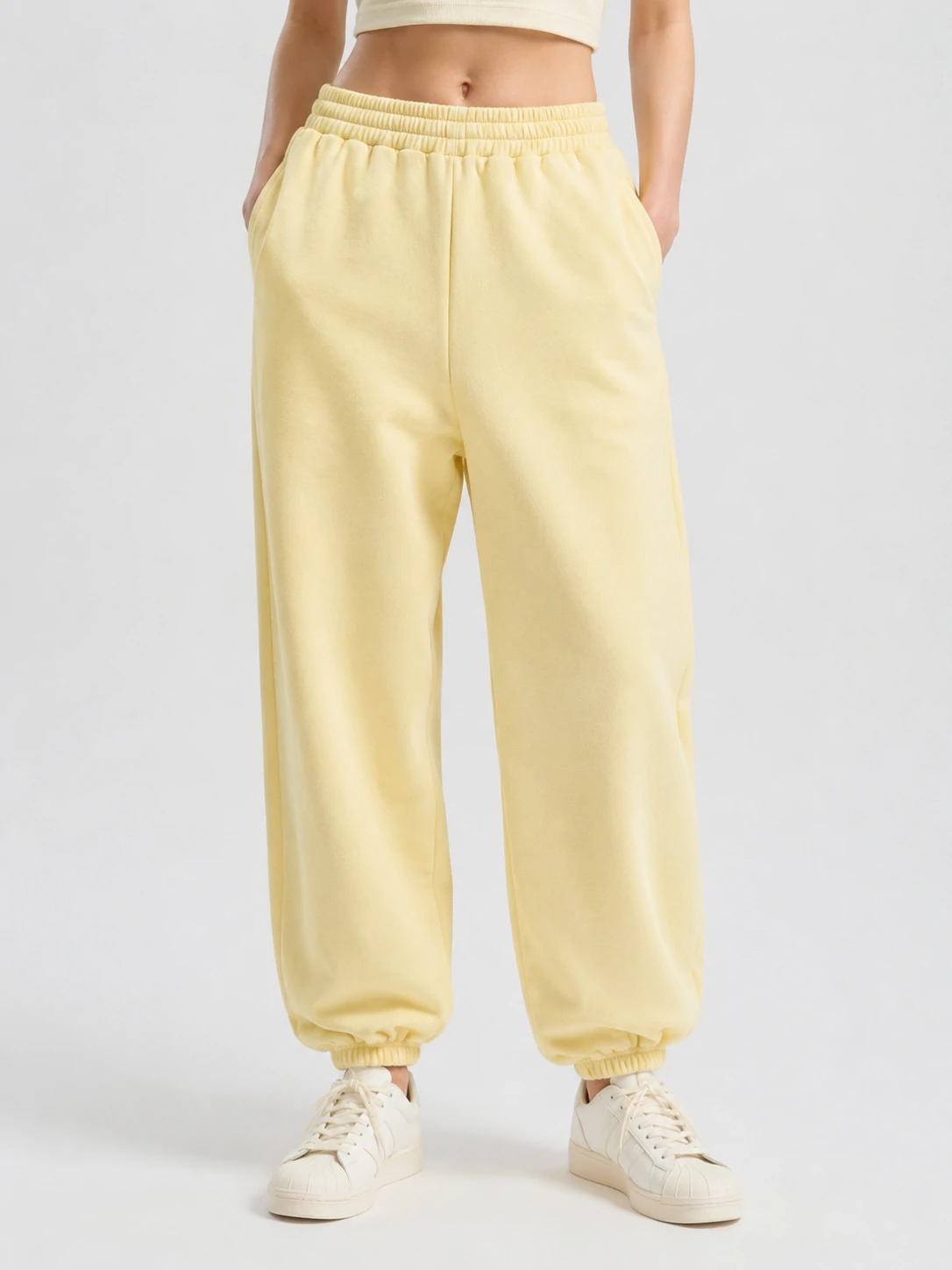 Model wearing butter yellow cuffed sweatpants with side pockets