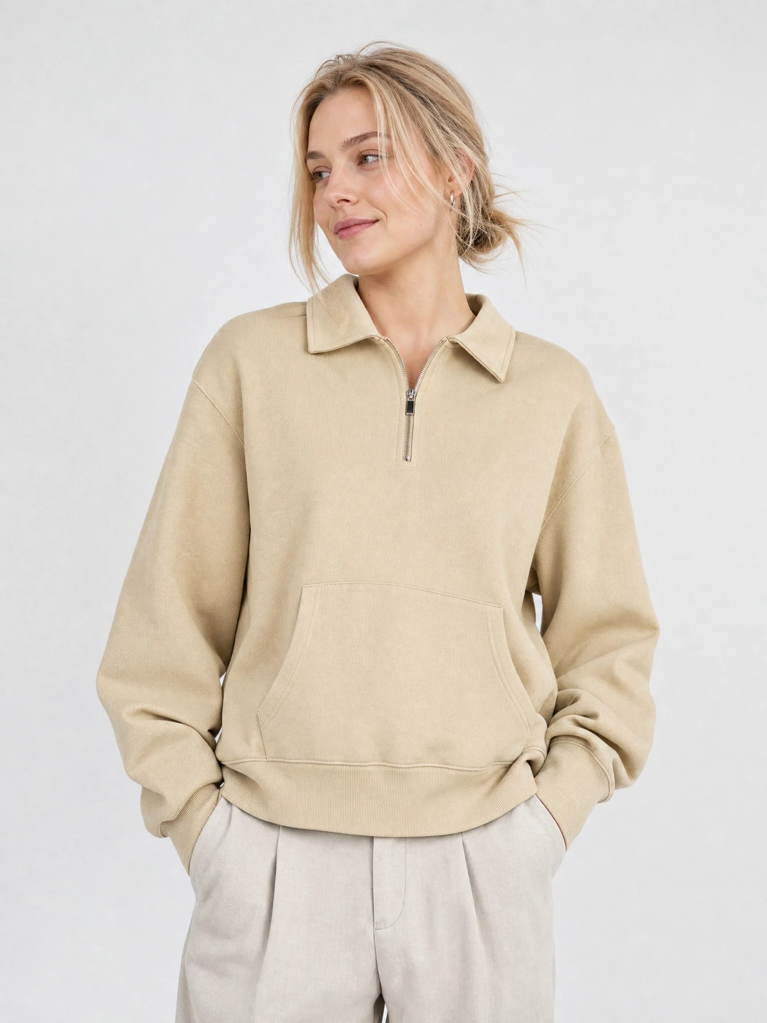 Woman wearing beige collared half-zip sweatshirt with kangaroo pocket