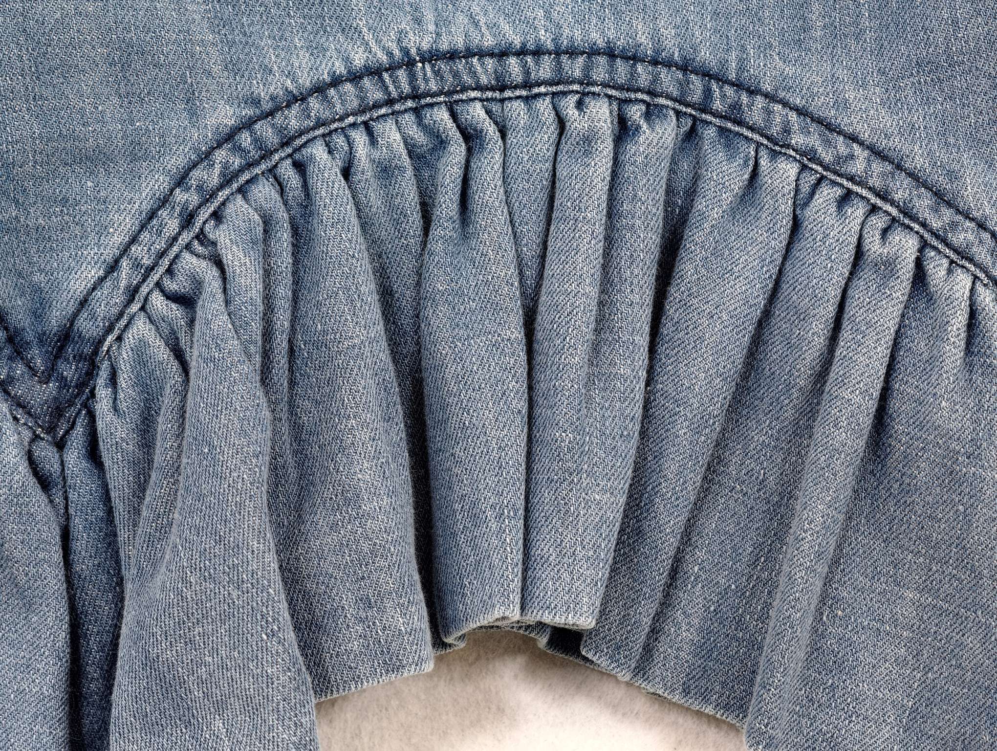 Curved seam joining gathered flounce hem on resort top