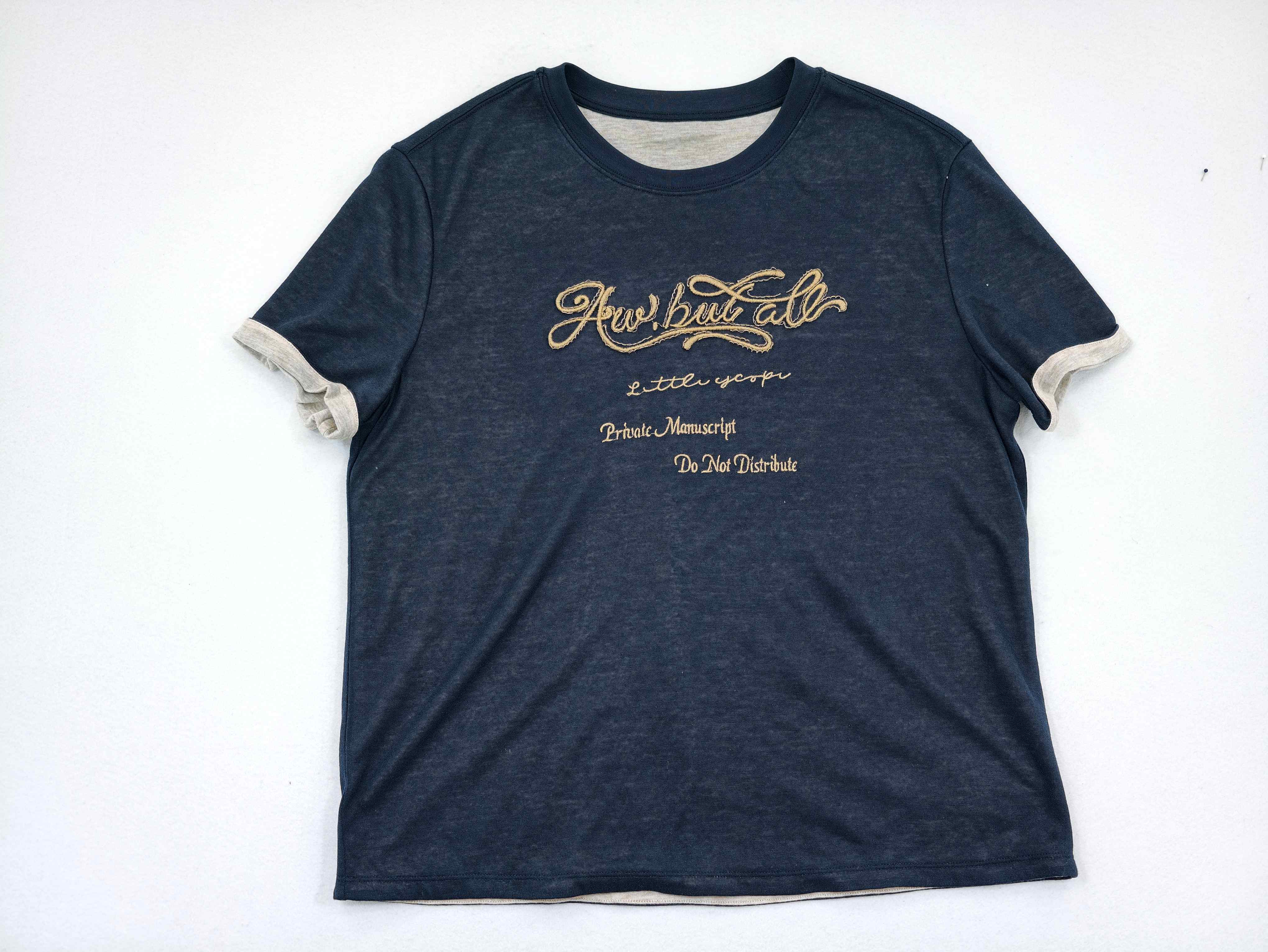 Flat front view showing script embroidery and loose silhouette