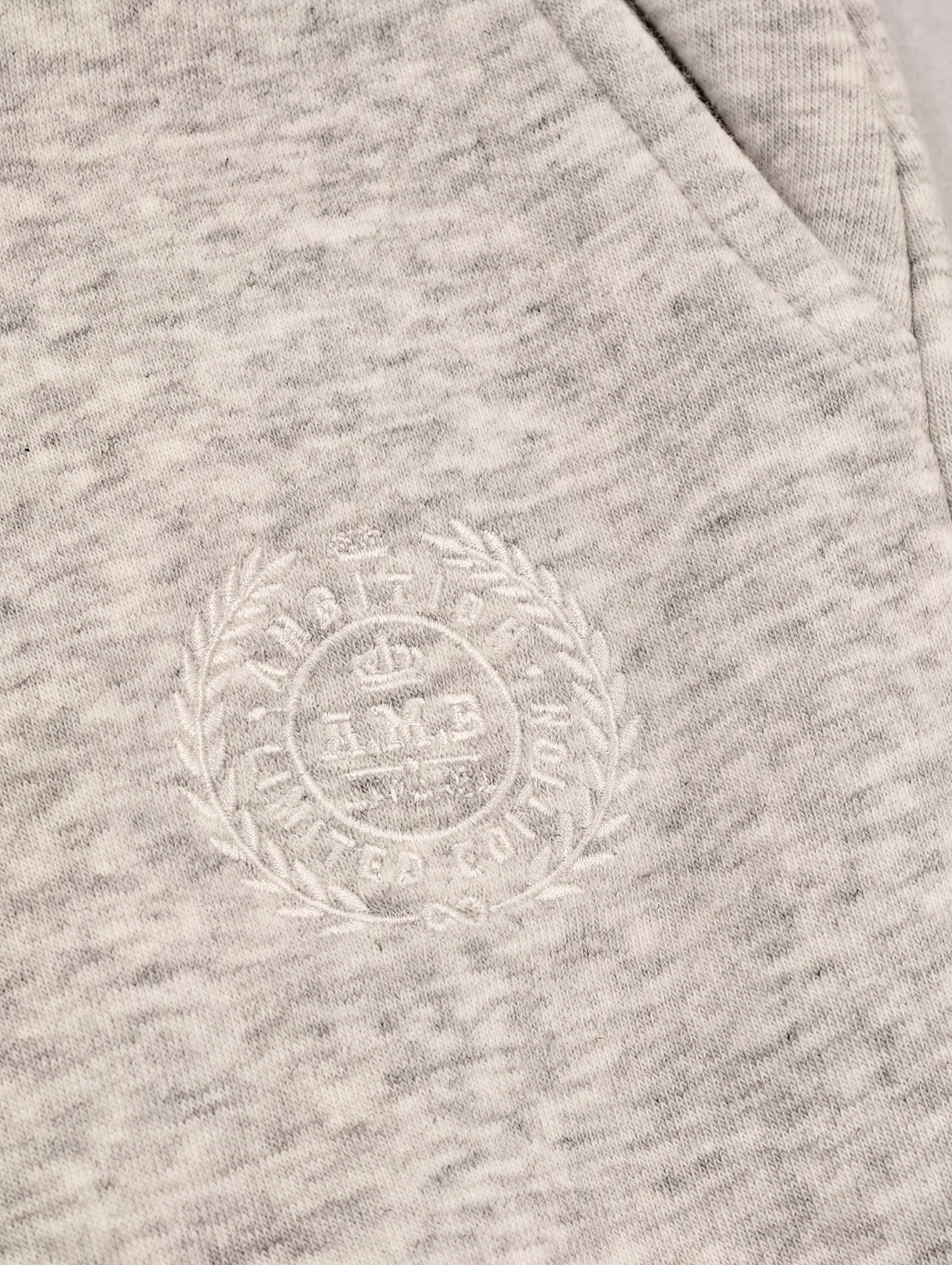 Tonal crest embroidery beside front pocket