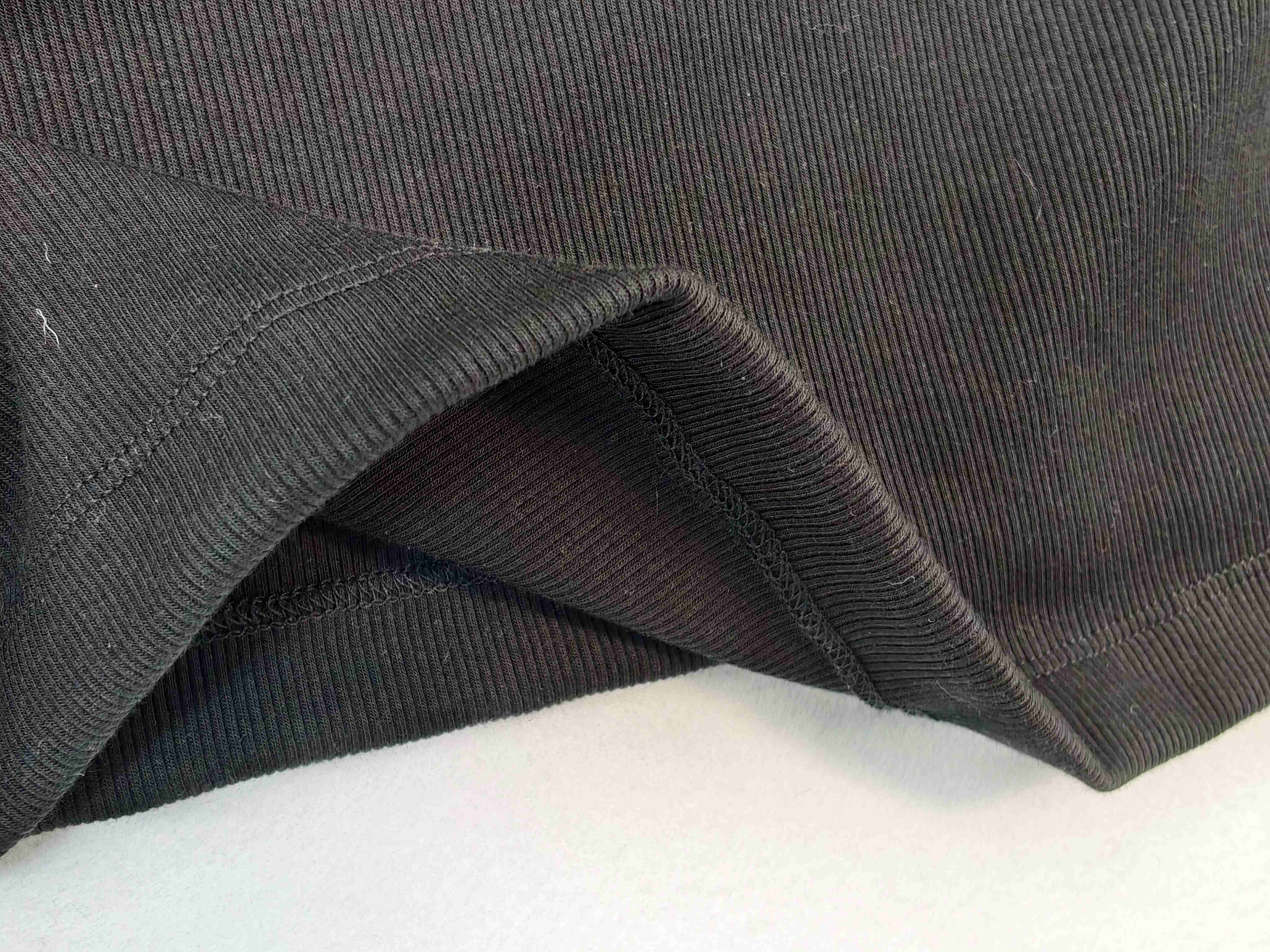 Black stretch-knit fabric with bound hem construction detail